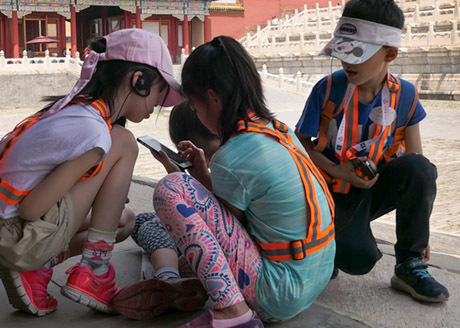small kids playing with their smartphone in the Forbidden City in Beijing, China